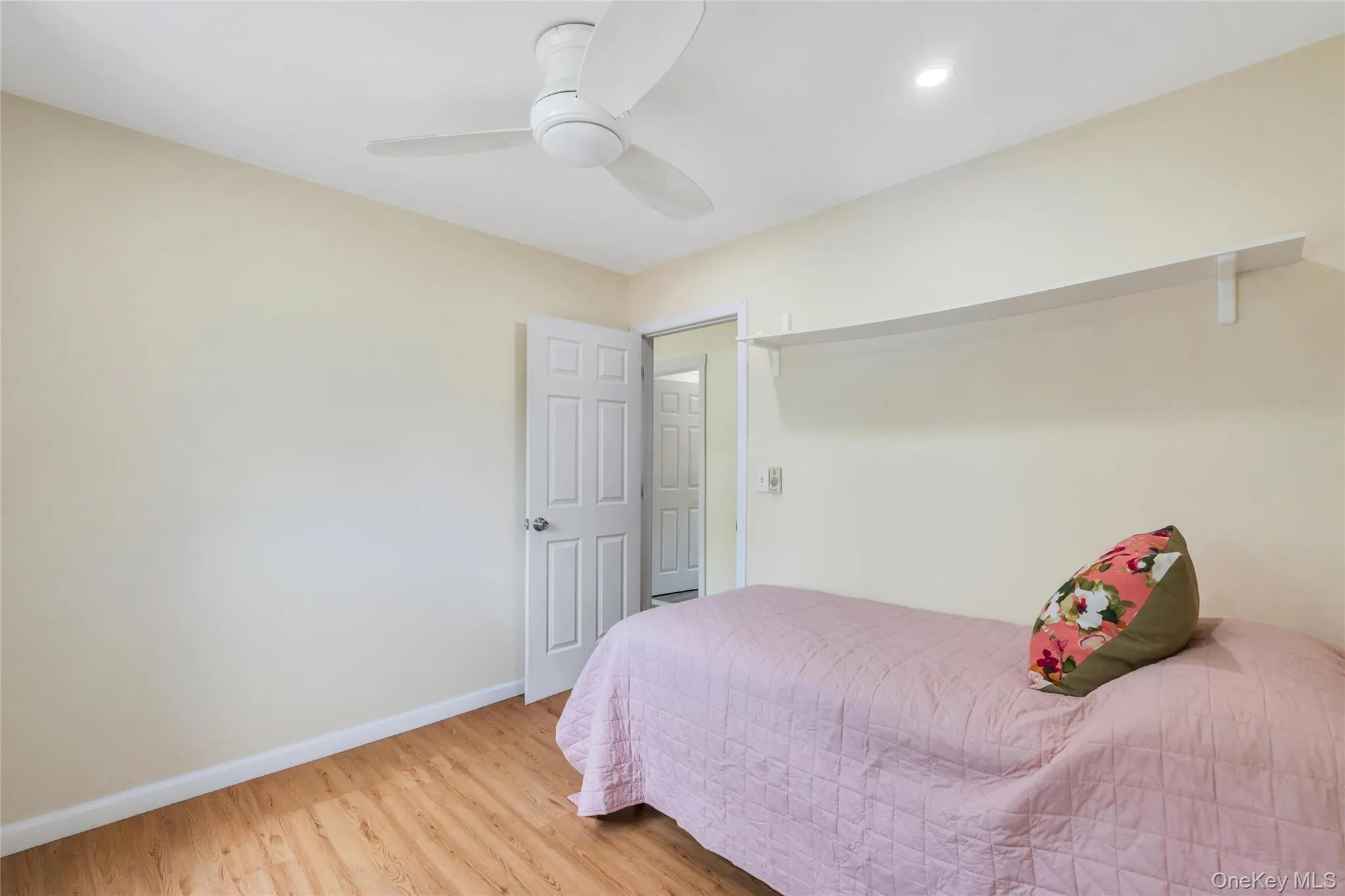 Room featuring wood-finish flooring, a contemporary ceiling fan with integrated lighting, and a white floating shelf Room featuring wood-finish flooring, a contemporary ceiling fan with integrated lighting, and a white floating shelf