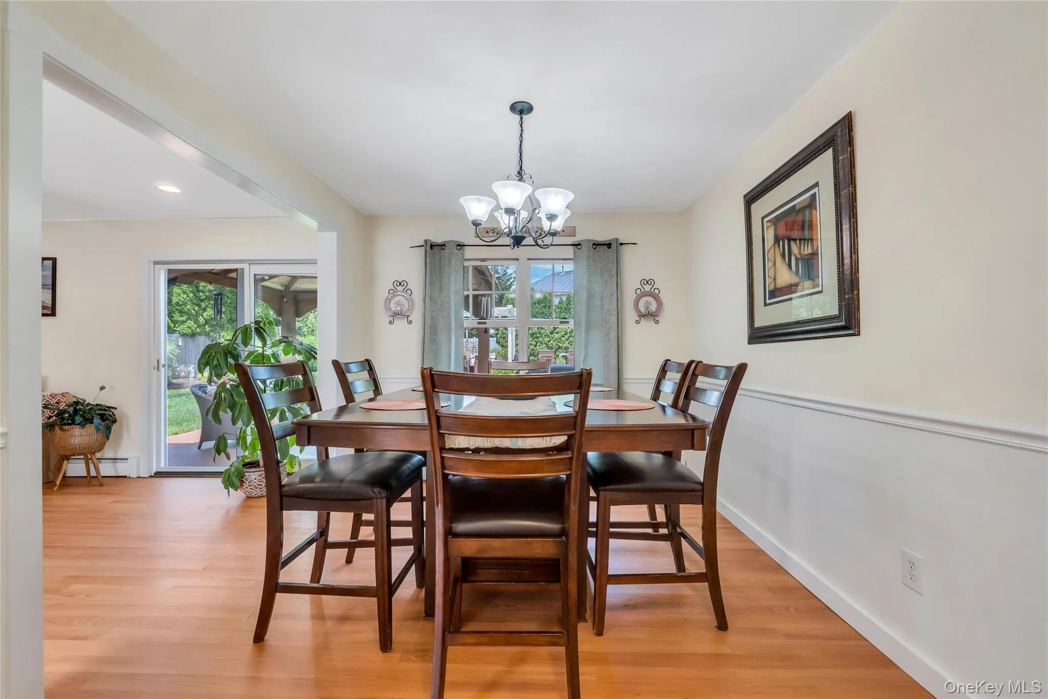 Dining area with wood-finish flooring, a multi-light chandelier, and wainscoting along the walls Dining area with wood-finish flooring, a multi-light chandelier, and wainscoting along the walls
