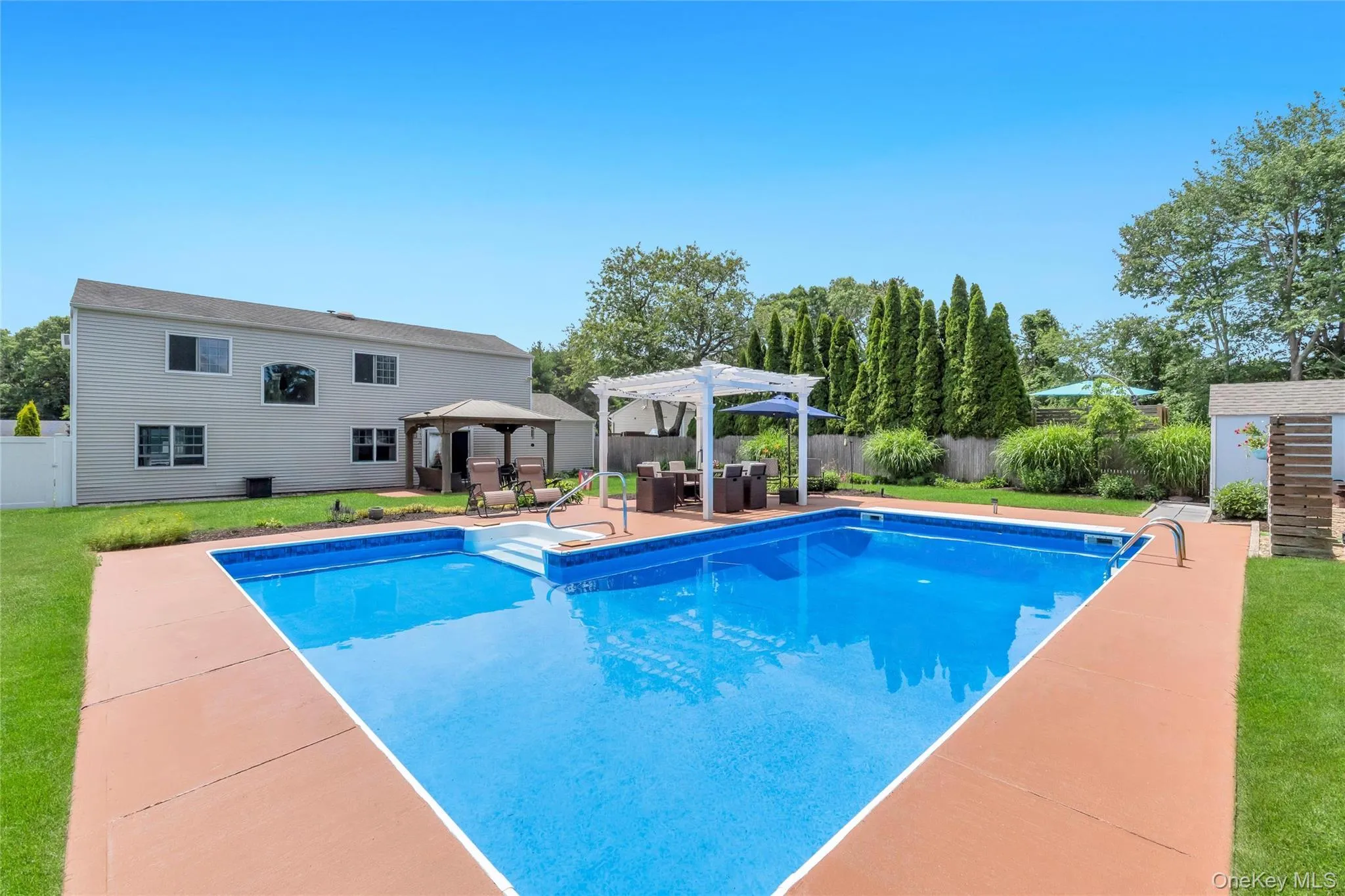 Expansive backyard featuring a rectangular in-ground pool, a white pergola, a covered gazebo, and a storage shed Expansive backyard featuring a rectangular in-ground pool, a white pergola, a covered gazebo, and a storage shed