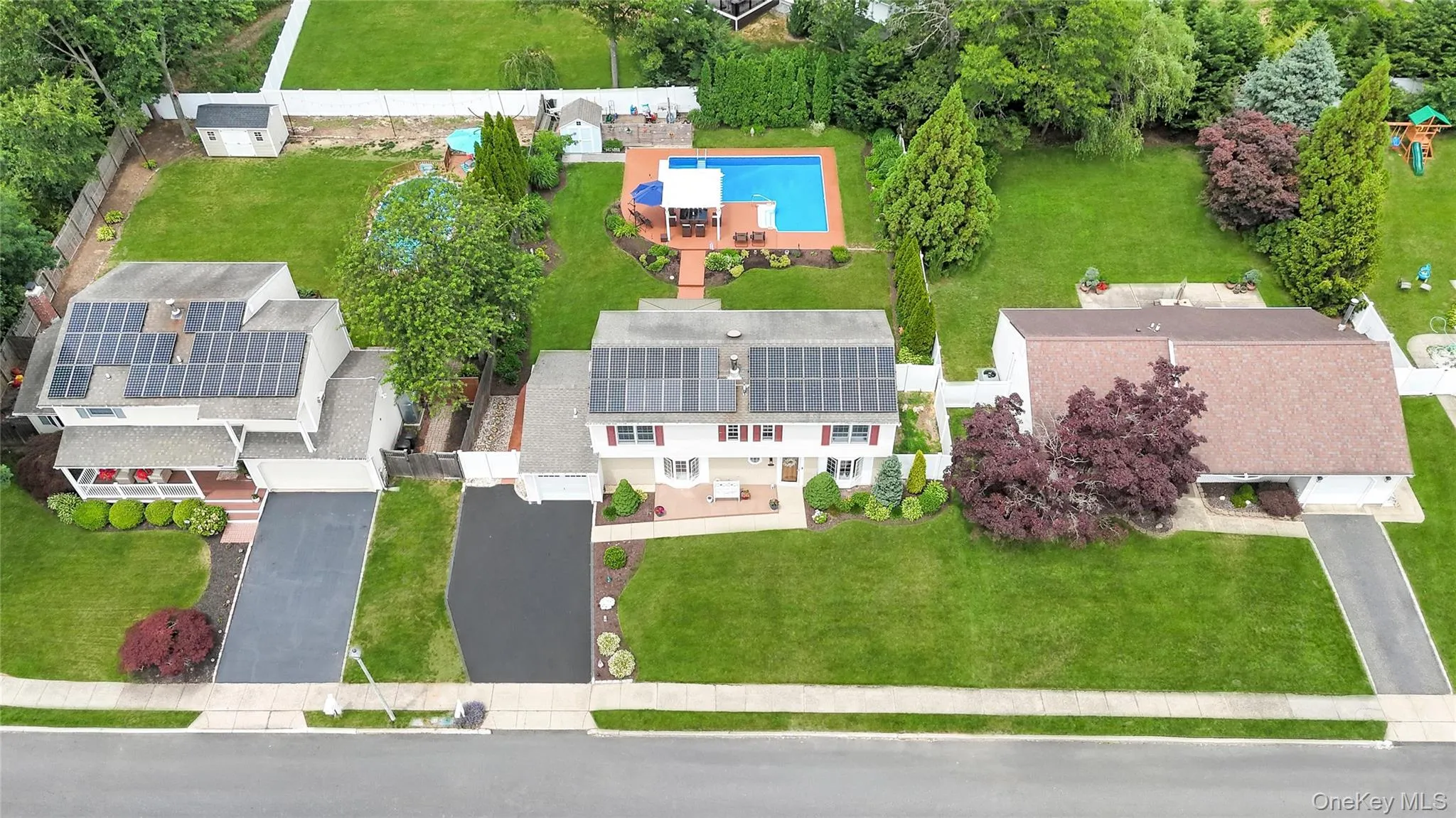 Aerial perspective showcasing a single-family residence with a substantial rear yard featuring an in-ground swimming pool and expansive green space Aerial perspective showcasing a single-family residence with a substantial rear yard featuring an in-ground swimming pool and expansive green space