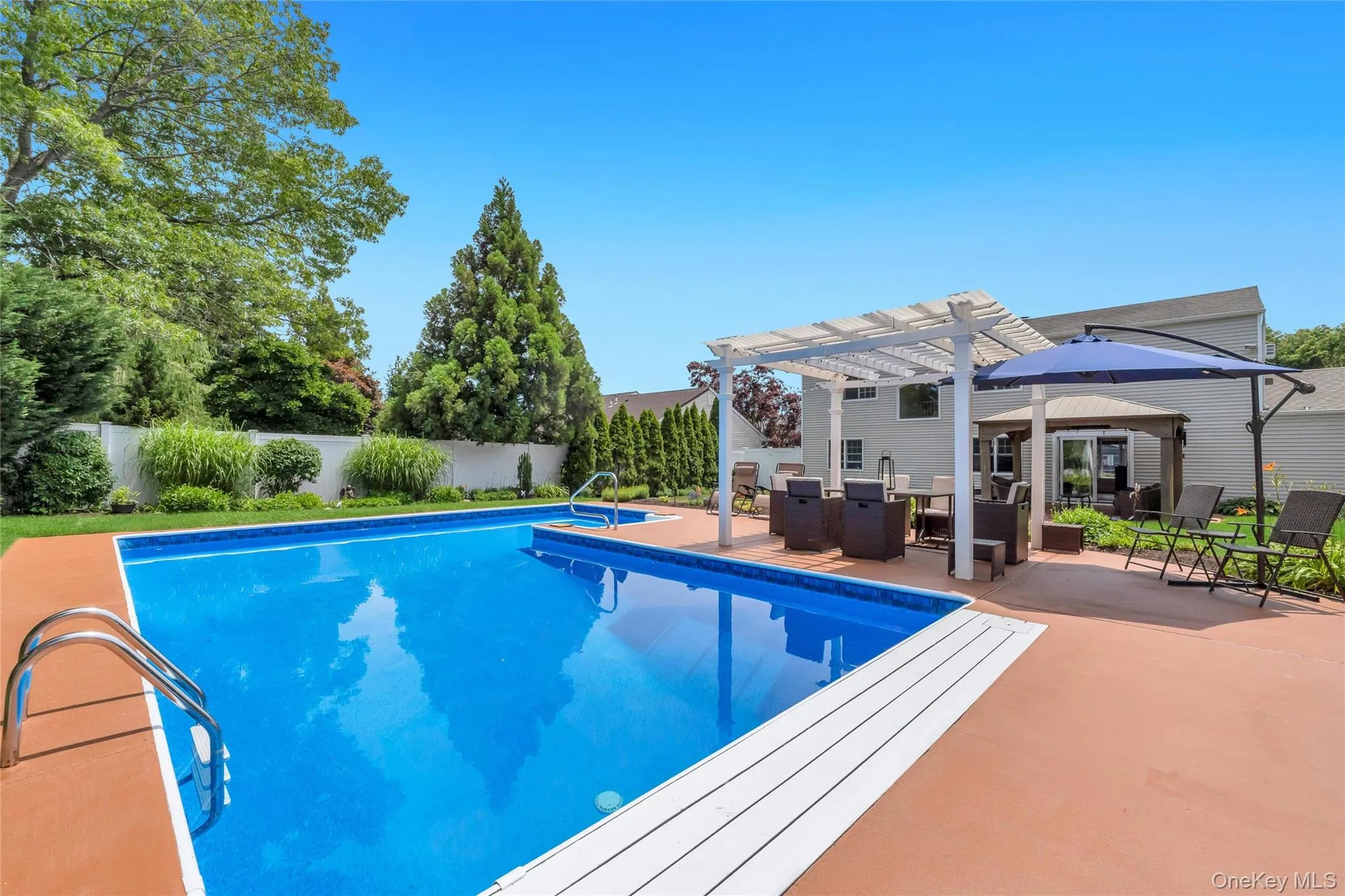 In-ground swimming pool featuring a tanning ledge and integrated spa In-ground swimming pool featuring a tanning ledge and integrated spa