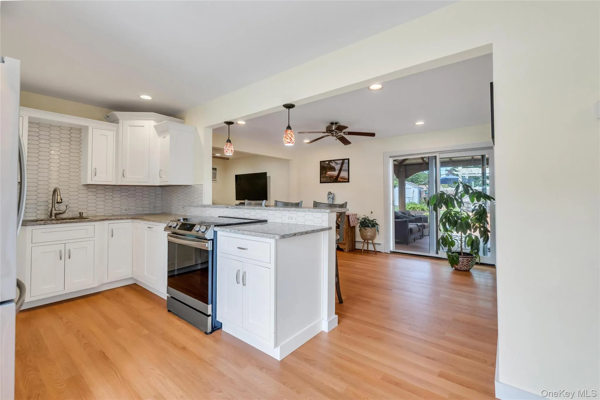 Kitchen featuring white shaker cabinetry, stainless steel range, and a patterned tile backsplash Kitchen featuring white shaker cabinetry, stainless steel range, and a patterned tile backsplash