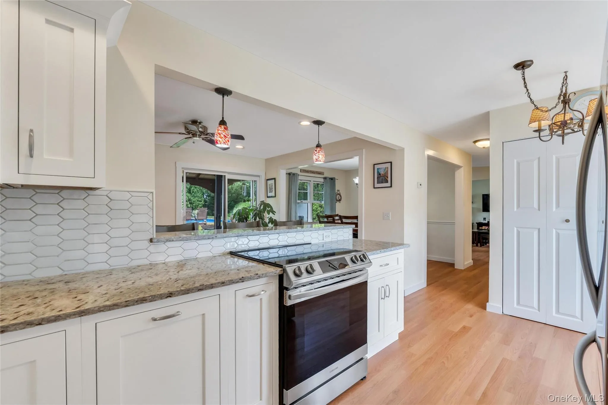 Modern kitchen featuring white shaker cabinetry, speckled countertops, a stainless steel range, and a geometric tile backsplash Modern kitchen featuring white shaker cabinetry, speckled countertops, a stainless steel range, and a geometric tile backsplash