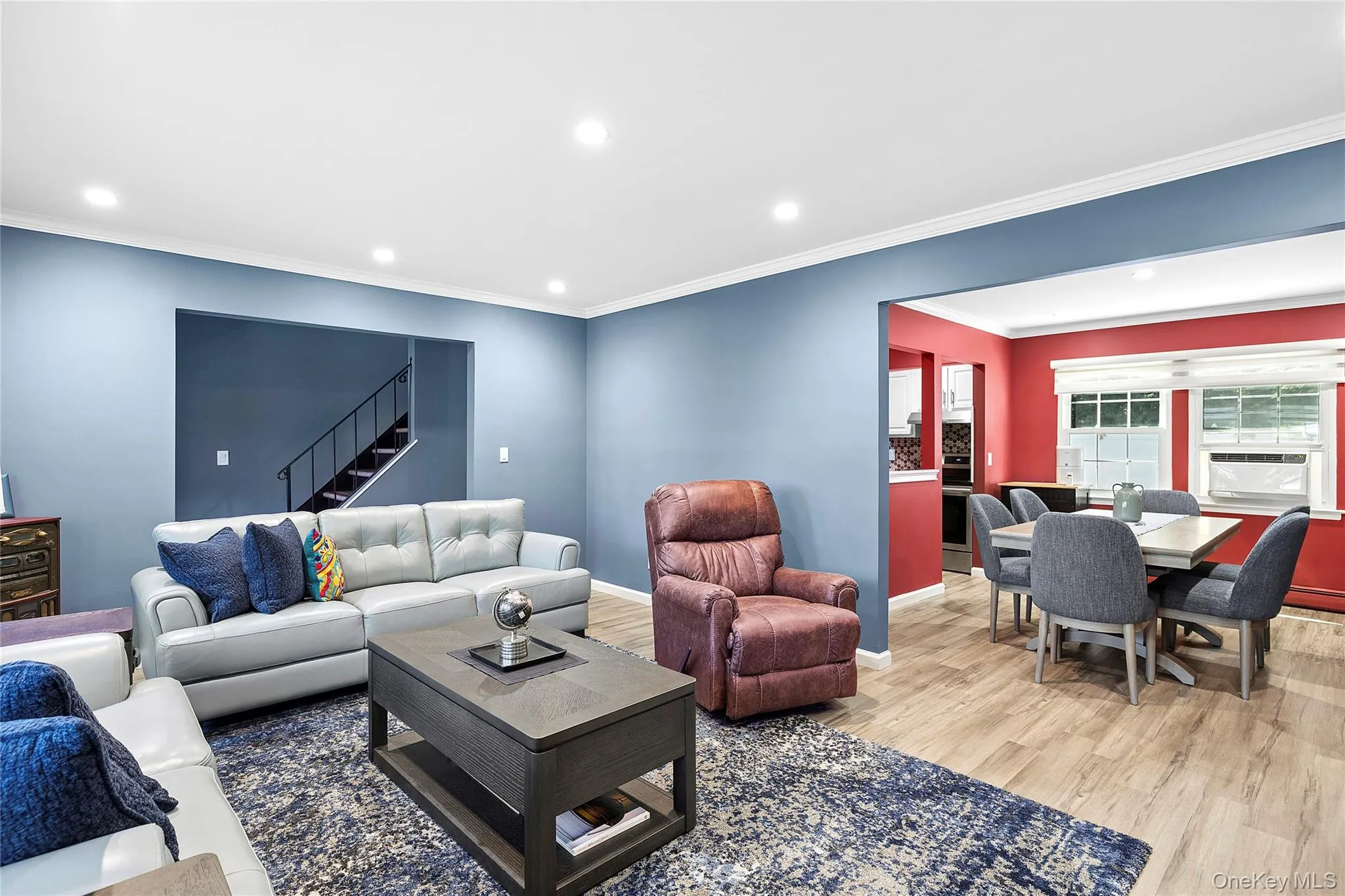 Open-concept living space featuring wood-finish flooring, recessed lighting, and crown molding Open-concept living space featuring wood-finish flooring, recessed lighting, and crown molding