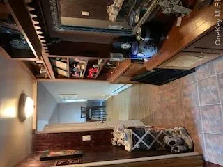 Hallway featuring tile flooring, built-in shelving, wood wall paneling, and an overhead flush-mount light fixture Hallway featuring tile flooring, built-in shelving, wood wall paneling, and an overhead flush-mount light fixture