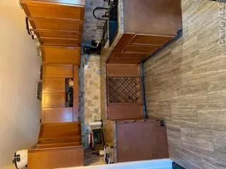 U-shaped kitchen featuring wood-finish cabinetry, tile backsplash, dark countertops, and wood-finish flooring U-shaped kitchen featuring wood-finish cabinetry, tile backsplash, dark countertops, and wood-finish flooring