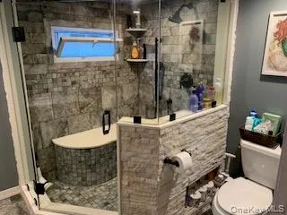 Enclosed glass shower featuring tile flooring, a built-in bench, and a wall-mounted showerhead Enclosed glass shower featuring tile flooring, a built-in bench, and a wall-mounted showerhead