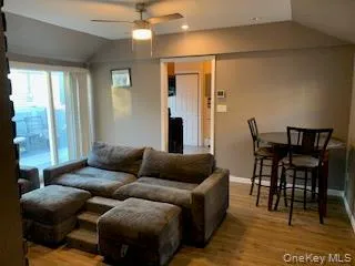 Living area featuring wood-finish flooring, vaulted ceiling, and recessed lighting Living area featuring wood-finish flooring, vaulted ceiling, and recessed lighting