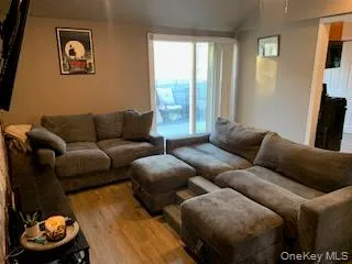 Living area featuring wood-finish flooring, neutral wall tones, and a sliding glass door providing access to an outdoor space Living area featuring wood-finish flooring, neutral wall tones, and a sliding glass door providing access to an outdoor space
