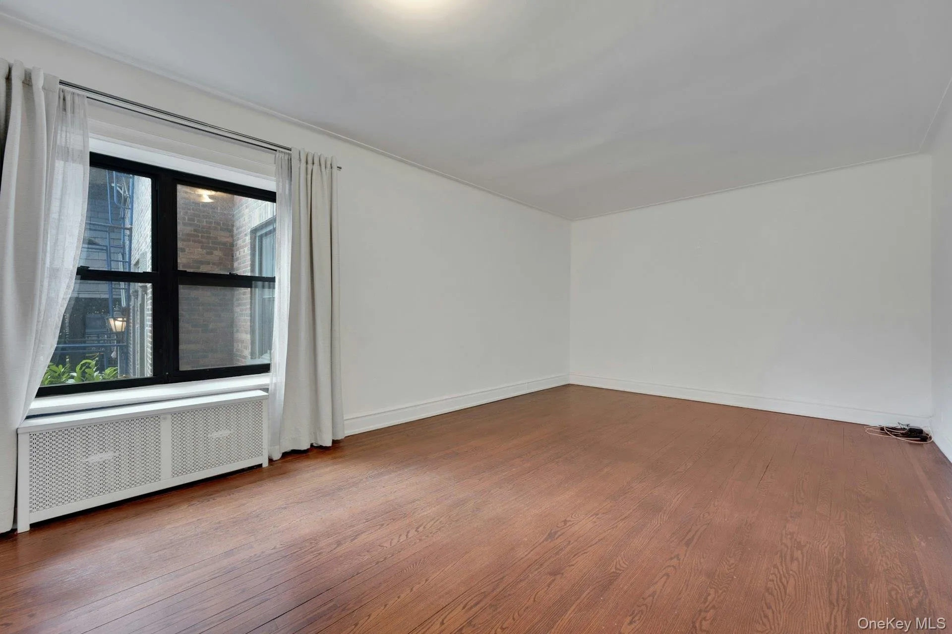 Spacious room with wood-finish flooring, white walls, and crown molding Spacious room with wood-finish flooring, white walls, and crown molding