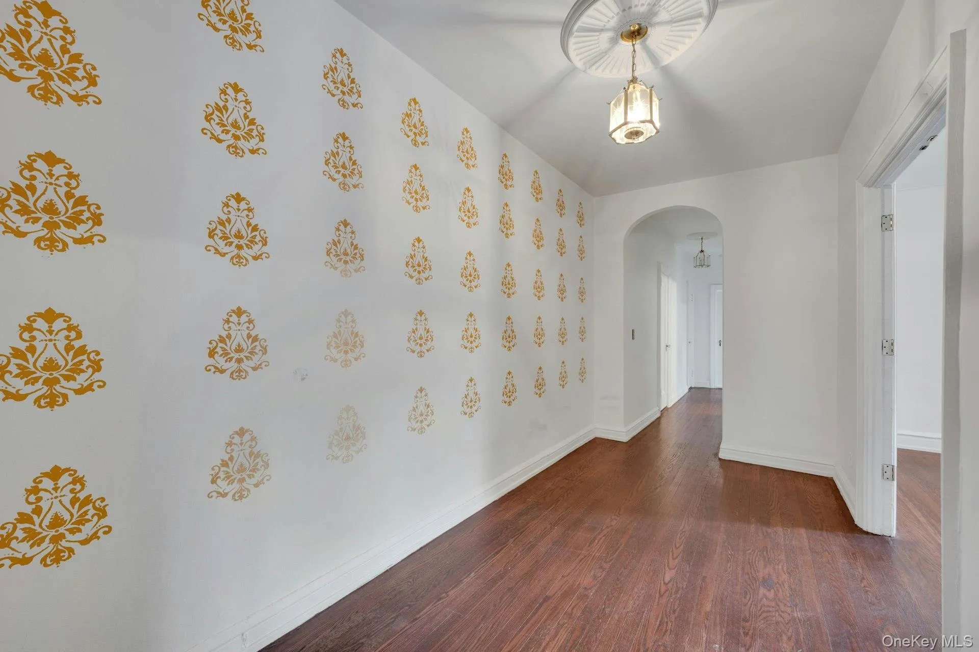 Entryway with wood-finish flooring, a decorative wall pattern, and a ceiling-mounted light fixture with a decorative medallion Entryway with wood-finish flooring, a decorative wall pattern, and a ceiling-mounted light fixture with a decorative medallion