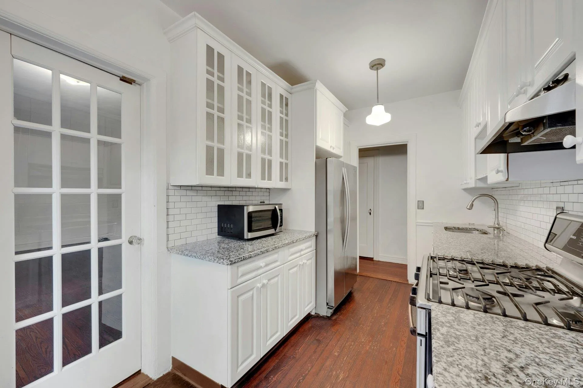 Kitchen featuring white cabinetry, subway tile backsplash, granite countertops, and stainless steel appliances Kitchen featuring white cabinetry, subway tile backsplash, granite countertops, and stainless steel appliances