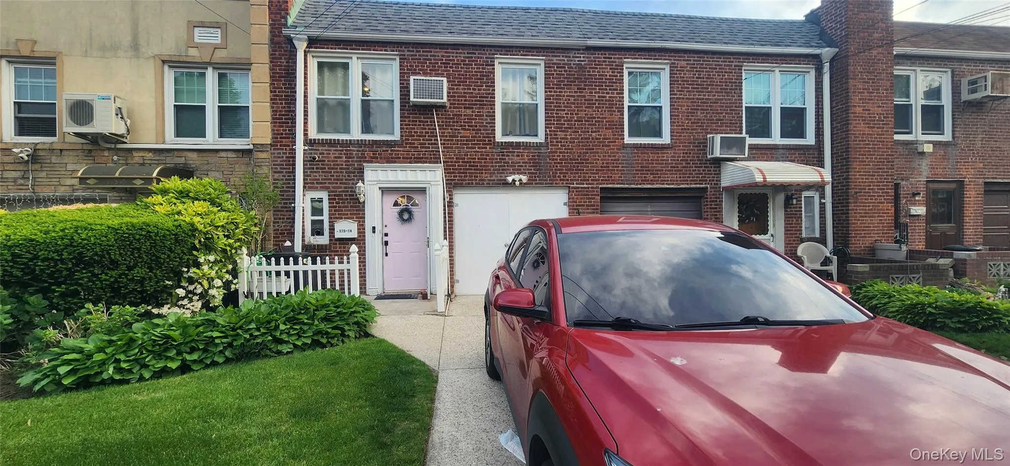 Multi unit property featuring ac unit, a garage, brick siding, and a shingled roof Multi unit property featuring ac unit, a garage, brick siding, and a shingled roof