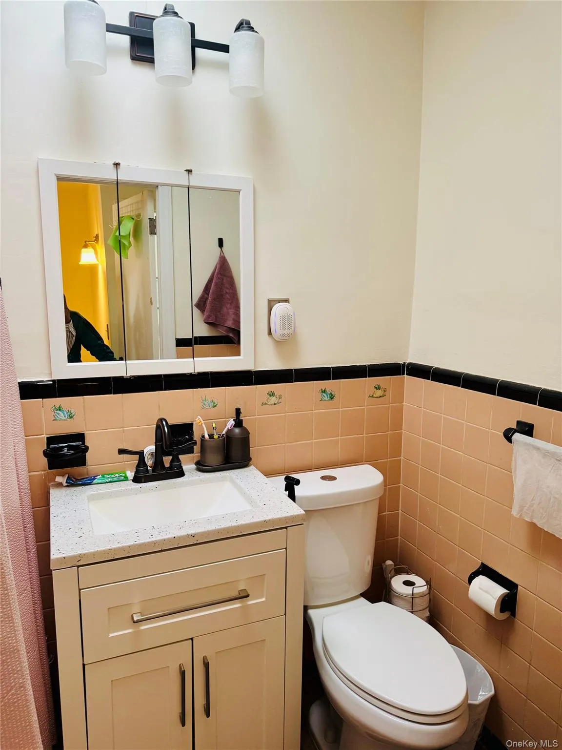 Bathroom with tile walls, vanity, a wainscoted wall, and toilet Bathroom with tile walls, vanity, a wainscoted wall, and toilet