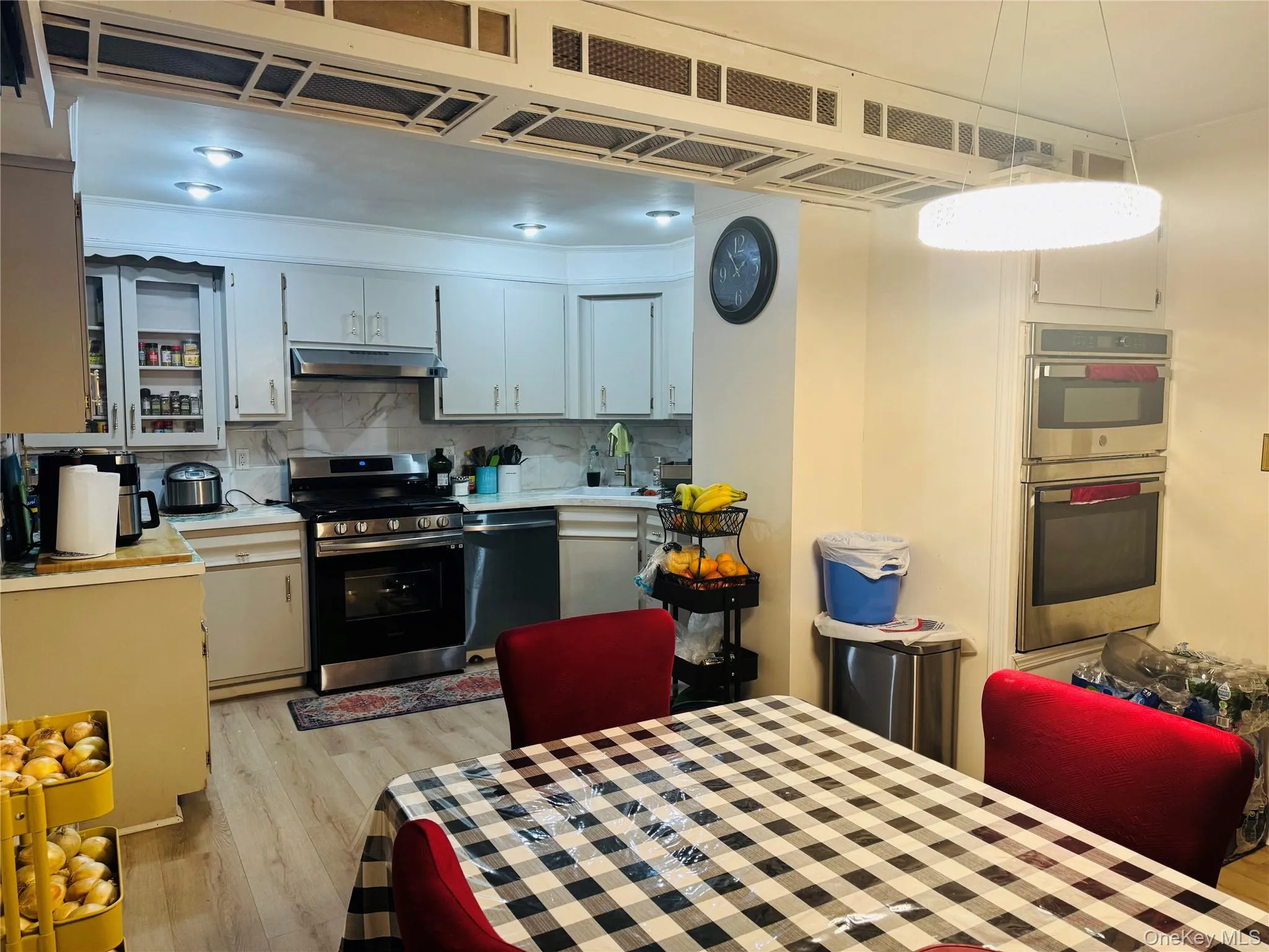 Kitchen featuring stainless steel appliances, light wood-style floors, under cabinet range hood, and light countertops Kitchen featuring stainless steel appliances, light wood-style floors, under cabinet range hood, and light countertops