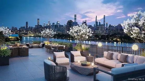 Expansive rooftop terrace with a riverfront backdrop, featuring multiple seating areas, a dining space, and integrated planters with flowering trees Expansive rooftop terrace with a riverfront backdrop, featuring multiple seating areas, a dining space, and integrated planters with flowering trees