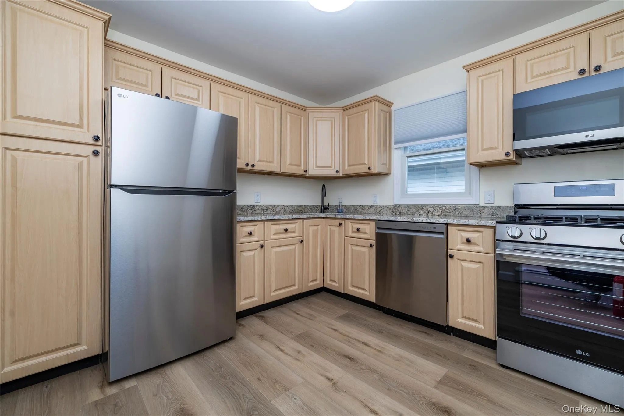 Kitchen featuring wood-finish cabinetry, granite countertops, and stainless steel appliances including a refrigerator, dishwasher, and range Kitchen featuring wood-finish cabinetry, granite countertops, and stainless steel appliances including a refrigerator, dishwasher, and range