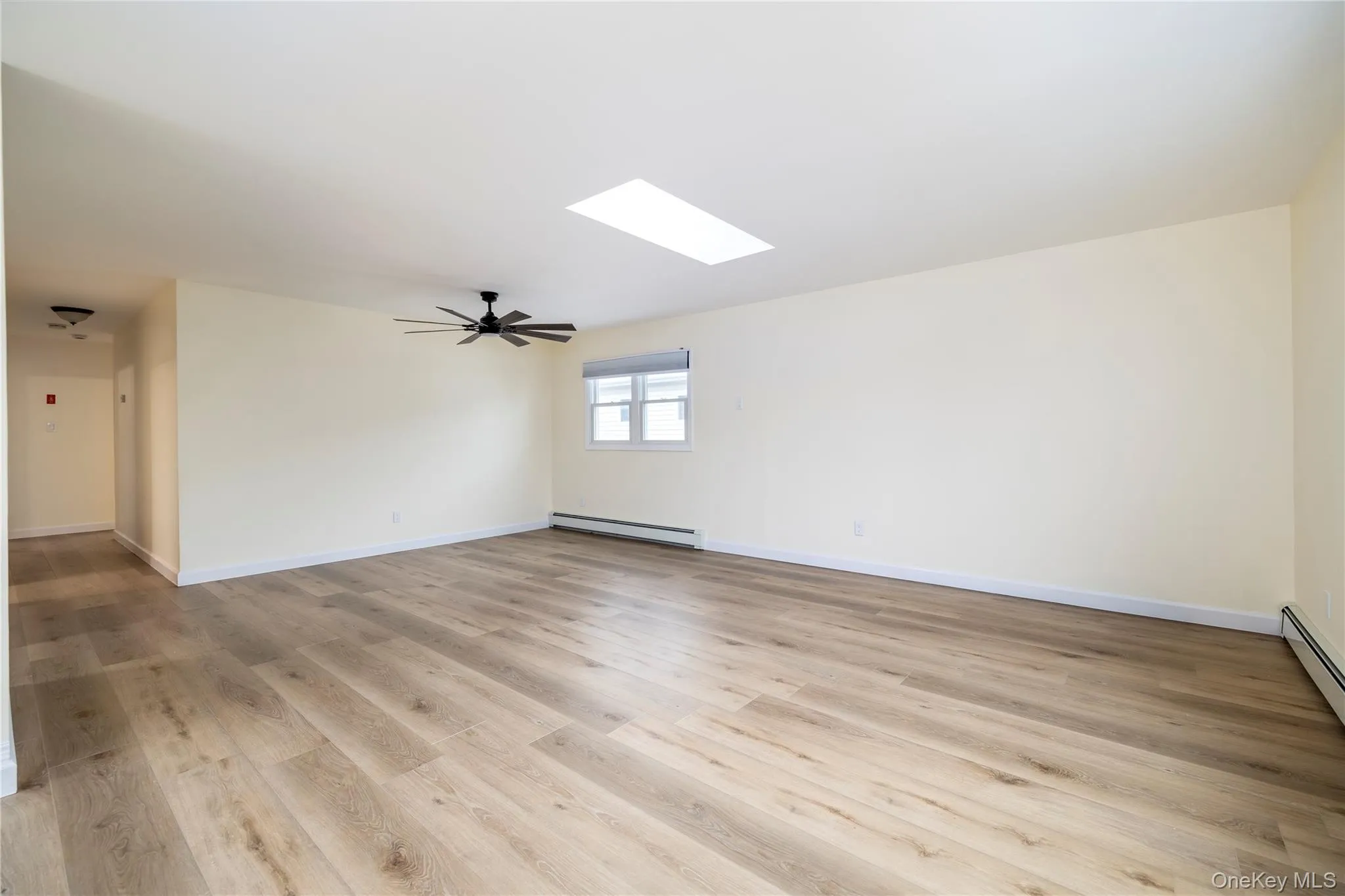 Spacious room featuring wood-finish flooring, a contemporary ceiling fan, and a skylight Spacious room featuring wood-finish flooring, a contemporary ceiling fan, and a skylight