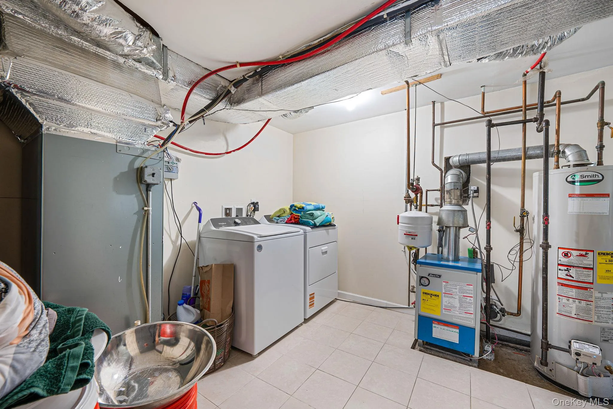 Washroom featuring water heater, washing machine and dryer, light tile patterned flooring, heating unit, and a heating unit Washroom featuring water heater, washing machine and dryer, light tile patterned flooring, heating unit, and a heating unit