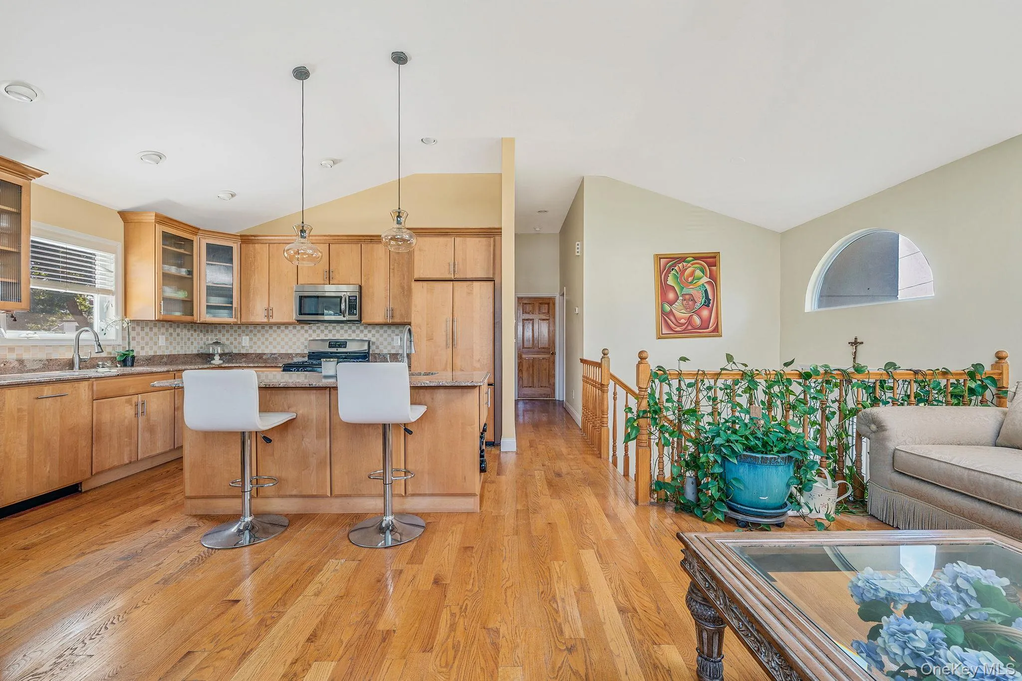 Kitchen with glass insert cabinets, light wood finished floors, open floor plan, a kitchen bar, and pendant lighting Kitchen with glass insert cabinets, light wood finished floors, open floor plan, a kitchen bar, and pendant lighting