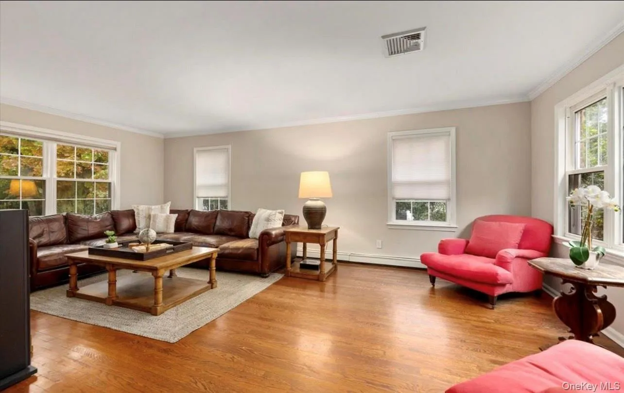 Living room featuring crown molding, wood finished floors, and a baseboard heating unit Living room featuring crown molding, wood finished floors, and a baseboard heating unit