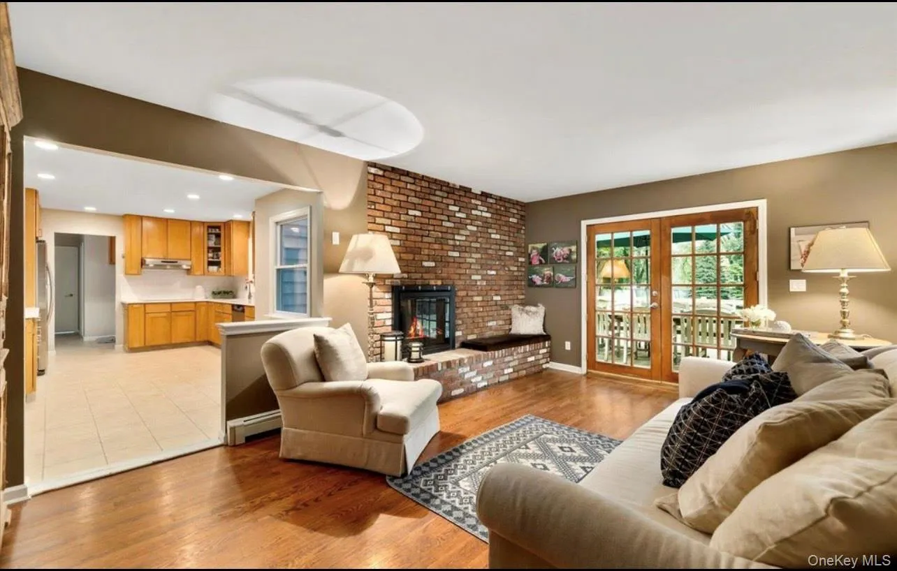 Living room with light wood-type flooring, a fireplace, recessed lighting, and a baseboard heating unit Living room with light wood-type flooring, a fireplace, recessed lighting, and a baseboard heating unit