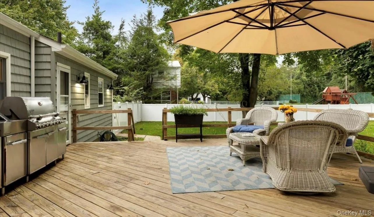 Wooden terrace with a fenced backyard, grilling area, outdoor dining space, and view of wooded area Wooden terrace with a fenced backyard, grilling area, outdoor dining space, and view of wooded area