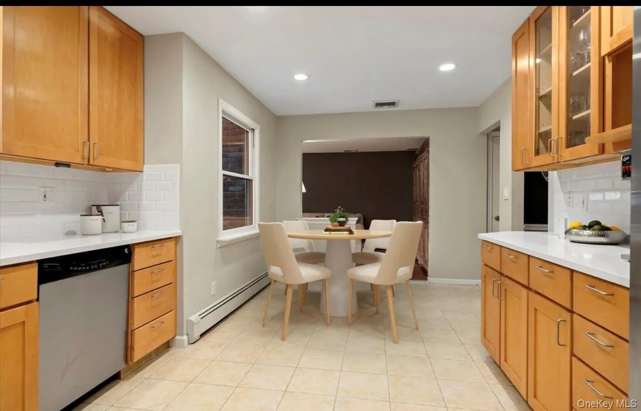 Kitchen featuring backsplash, a baseboard heating unit, stainless steel dishwasher, light countertops, and recessed lighting Kitchen featuring backsplash, a baseboard heating unit, stainless steel dishwasher, light countertops, and recessed lighting
