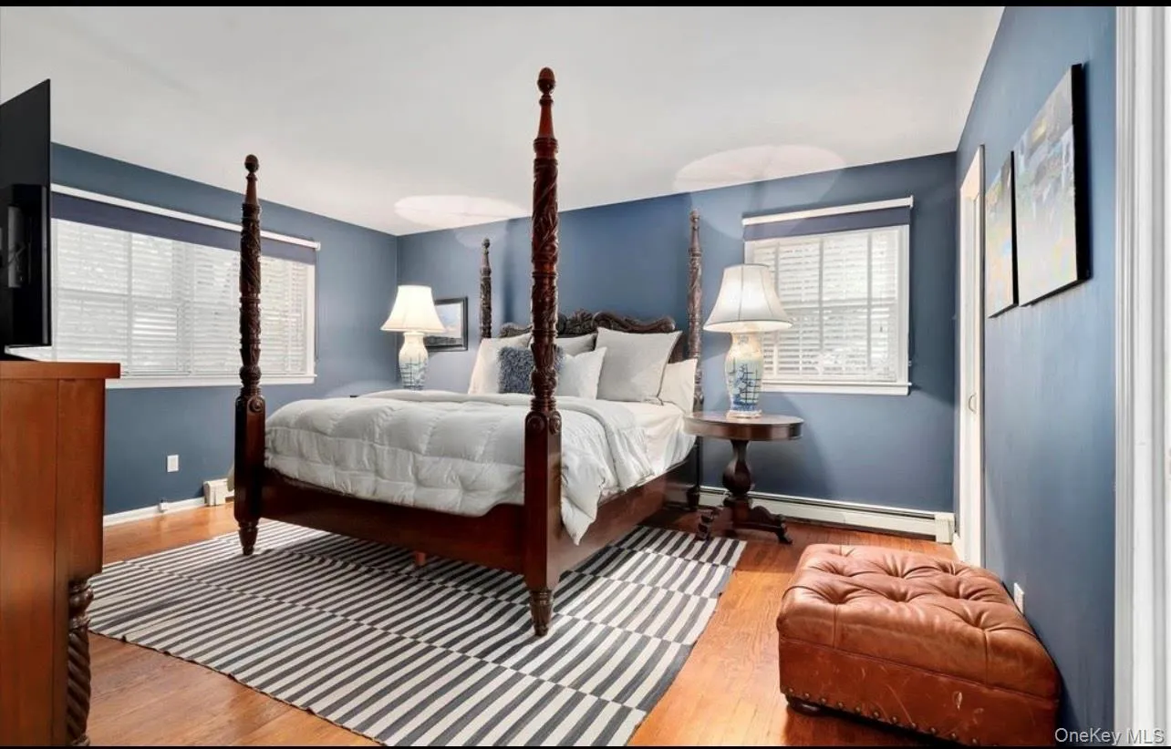Bedroom with multiple windows, wood finished floors, and a baseboard radiator Bedroom with multiple windows, wood finished floors, and a baseboard radiator
