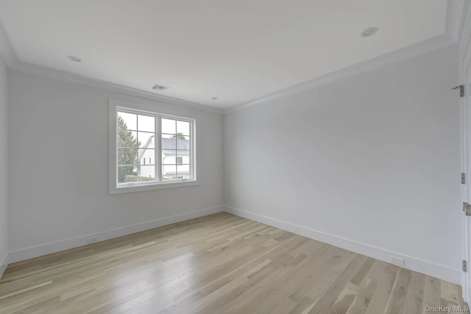 Unfurnished room featuring light wood-style floors, crown molding, and baseboards Unfurnished room featuring light wood-style floors, crown molding, and baseboards
