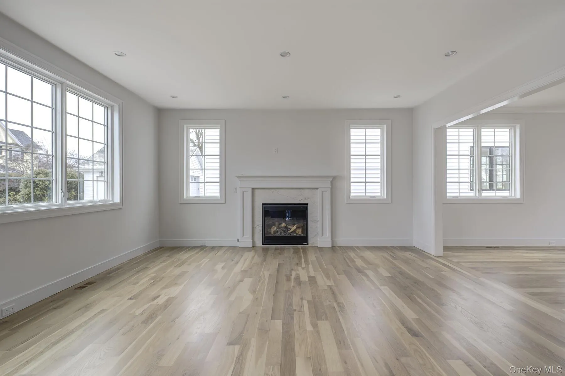 Unfurnished living room with light wood-type flooring and a healthy amount of sunlight Unfurnished living room with light wood-type flooring and a healthy amount of sunlight