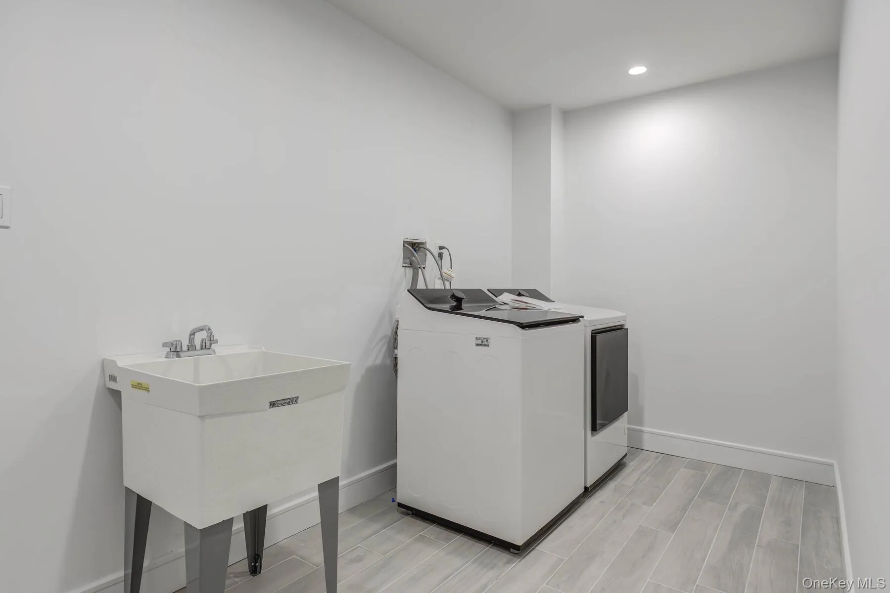 Laundry room with laundry area, baseboards, washer and dryer, wood finish floors, and a sink Laundry room with laundry area, baseboards, washer and dryer, wood finish floors, and a sink