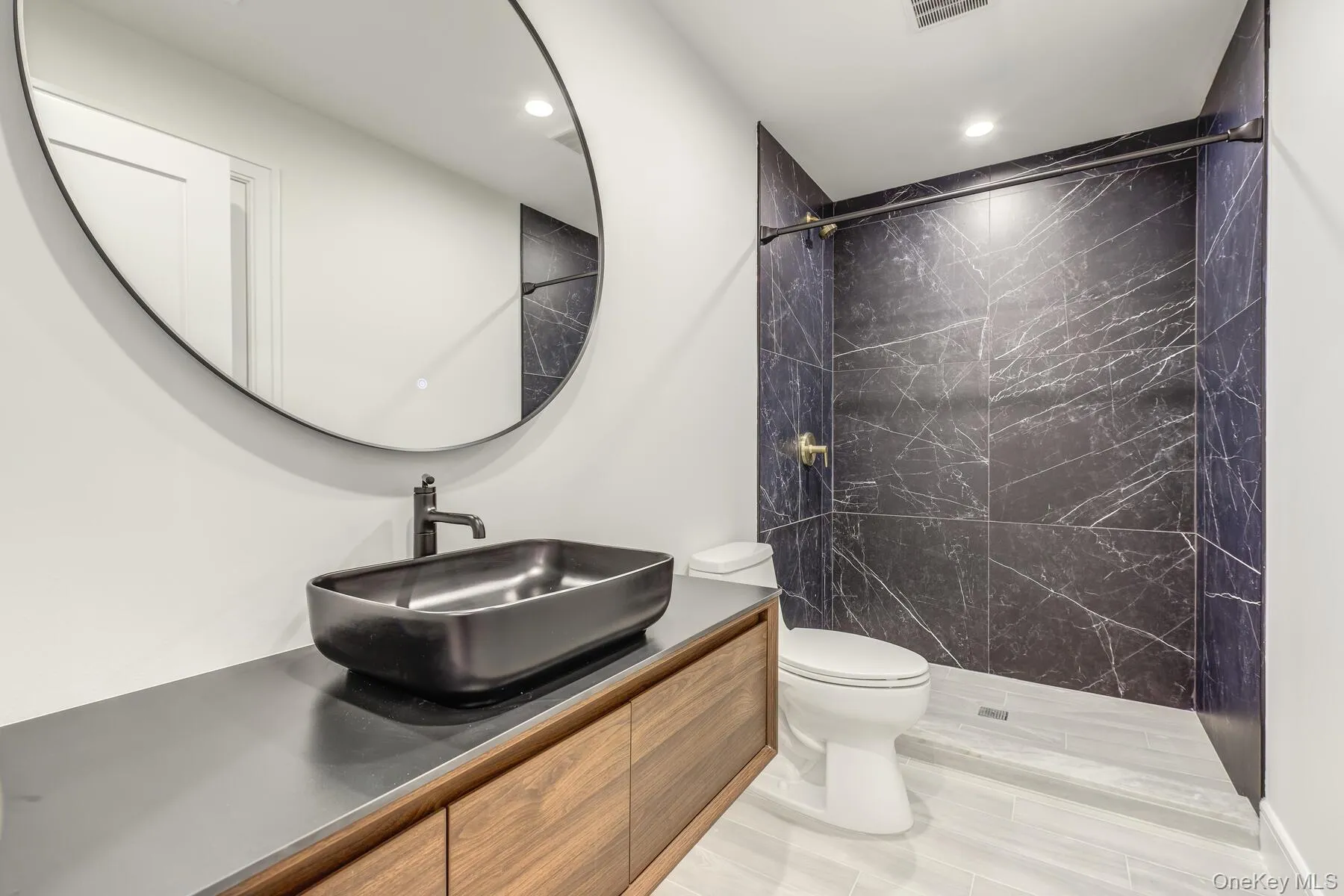 Bathroom with visible vents, vanity, a tile shower, and toilet Bathroom with visible vents, vanity, a tile shower, and toilet