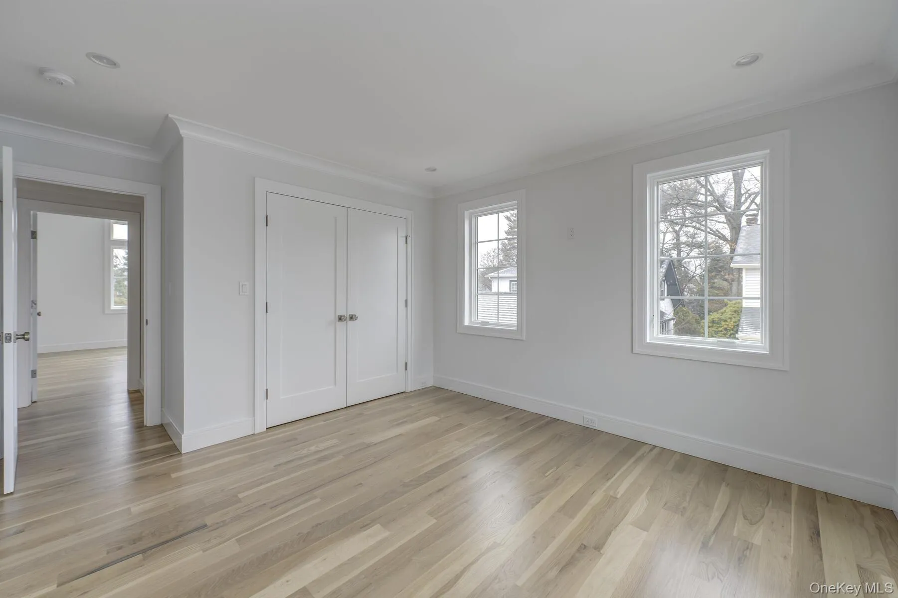 Unfurnished bedroom featuring baseboards, crown molding, and light wood finished floors Unfurnished bedroom featuring baseboards, crown molding, and light wood finished floors