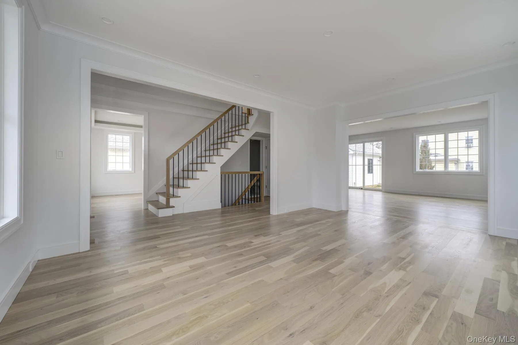 Empty room with a healthy amount of sunlight, light wood-style floors, stairway, and crown molding Empty room with a healthy amount of sunlight, light wood-style floors, stairway, and crown molding