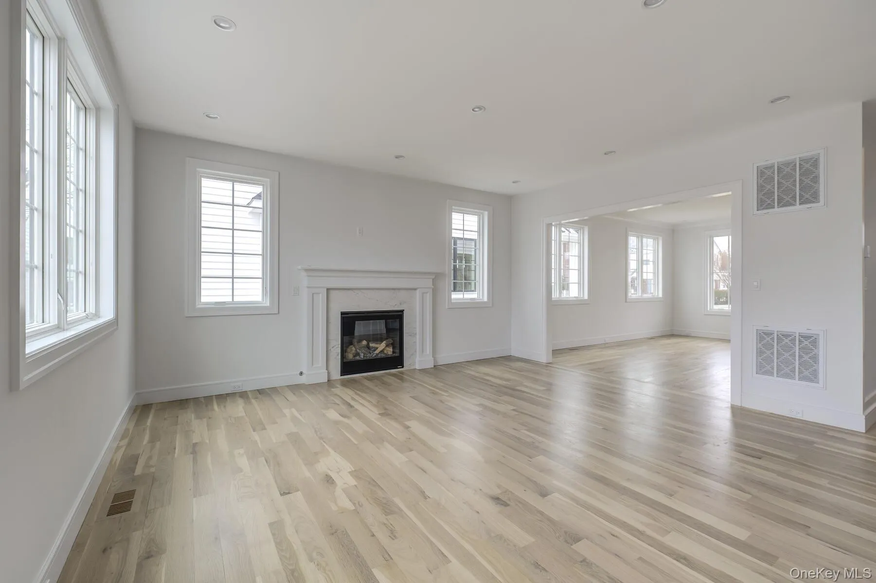 Unfurnished living room with light wood-type flooring, a premium fireplace, and visible vents Unfurnished living room with light wood-type flooring, a premium fireplace, and visible vents