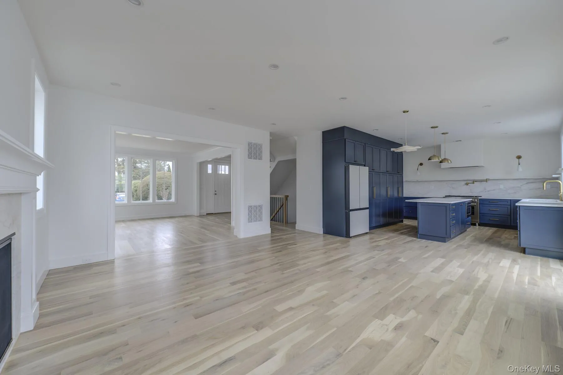 Unfurnished living room with baseboards, visible vents, a glass covered fireplace, light wood-type flooring, and a sink Unfurnished living room with baseboards, visible vents, a glass covered fireplace, light wood-type flooring, and a sink
