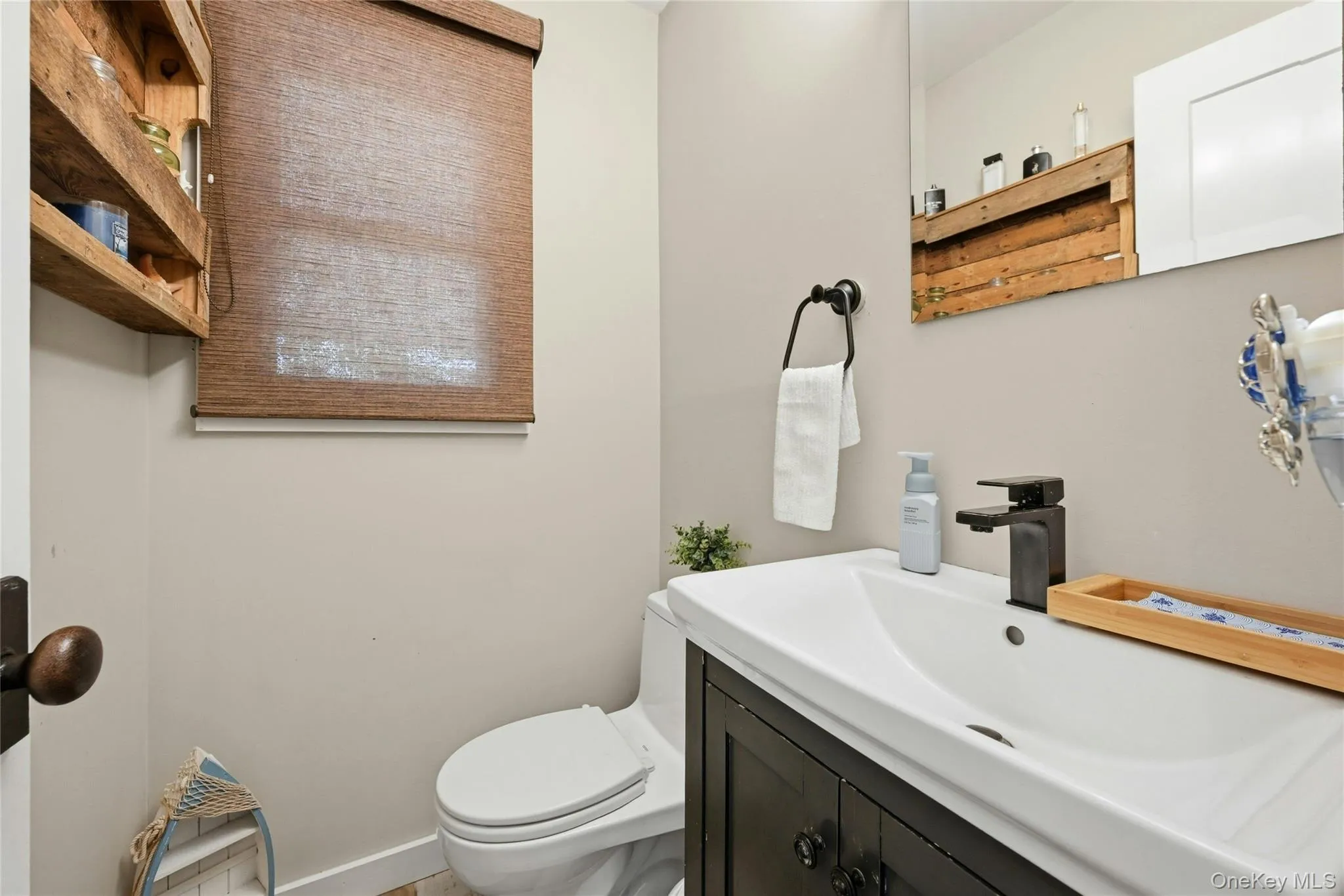 1/2 Bathroom featuring a dark wood-finish vanity with an integrated sink, matte black faucet, and coordinating towel ring 1/2 Bathroom featuring a dark wood-finish vanity with an integrated sink, matte black faucet, and coordinating towel ring