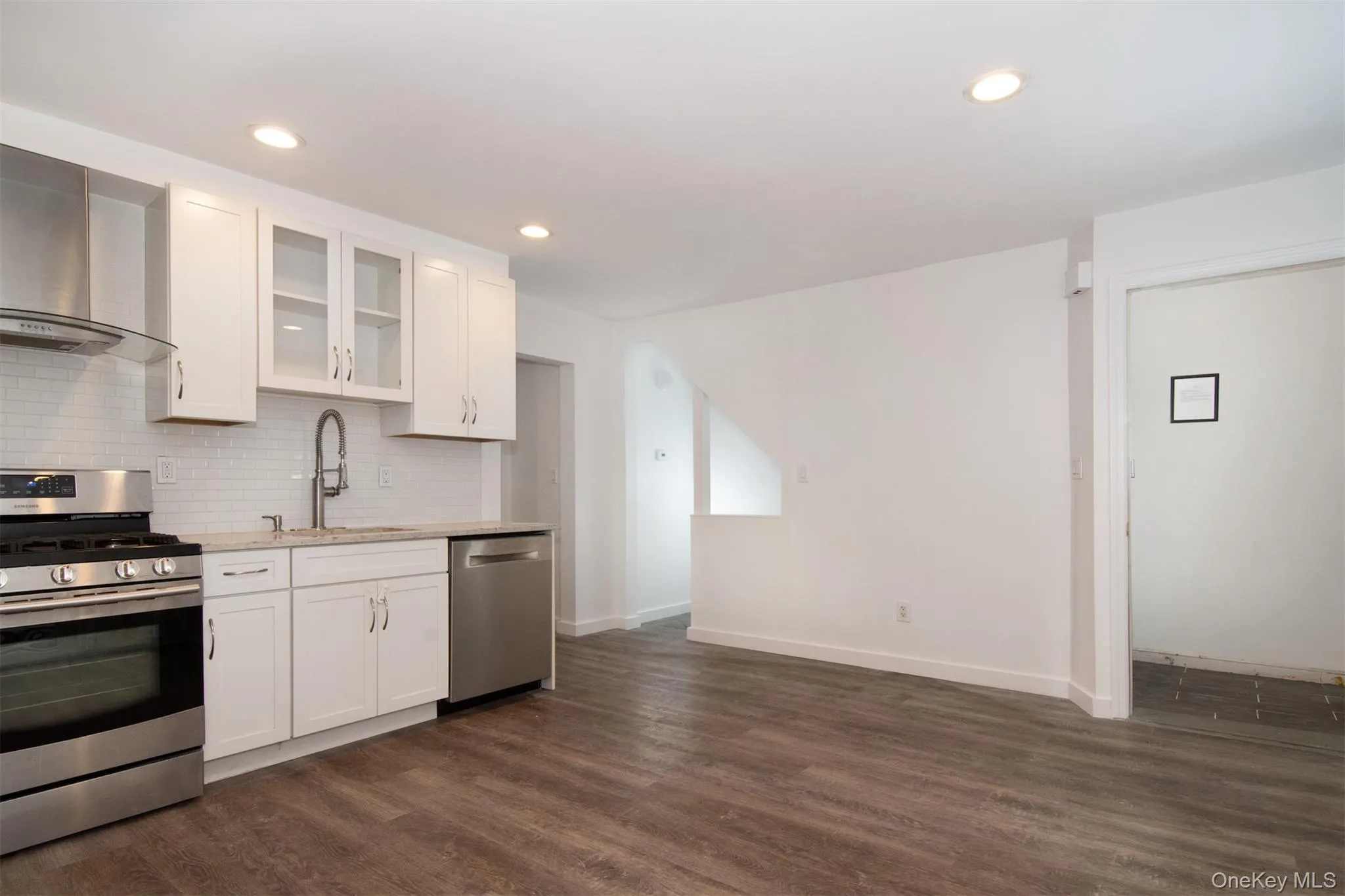 Kitchen with stainless steel appliances, dark hardwood / wood-style flooring, white cabinetry, and sink Kitchen with stainless steel appliances, dark hardwood / wood-style flooring, white cabinetry, and sink