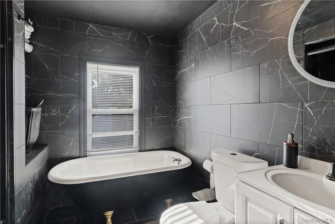 2nd floor Bathroom with a deep soaking clawfoot bathtub, toilet, and tile walls 2nd floor Bathroom with a deep soaking clawfoot bathtub, toilet, and tile walls