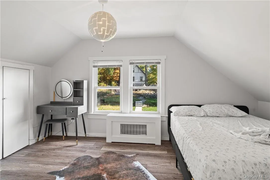 Bedroom featuring radiator heating unit, vaulted ceiling, and wood-type flooring Bedroom featuring radiator heating unit, vaulted ceiling, and wood-type flooring