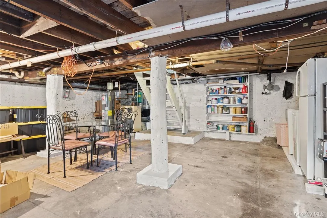 Basement with white refrigerator, washer, dryer, and water heater Basement with white refrigerator, washer, dryer, and water heater