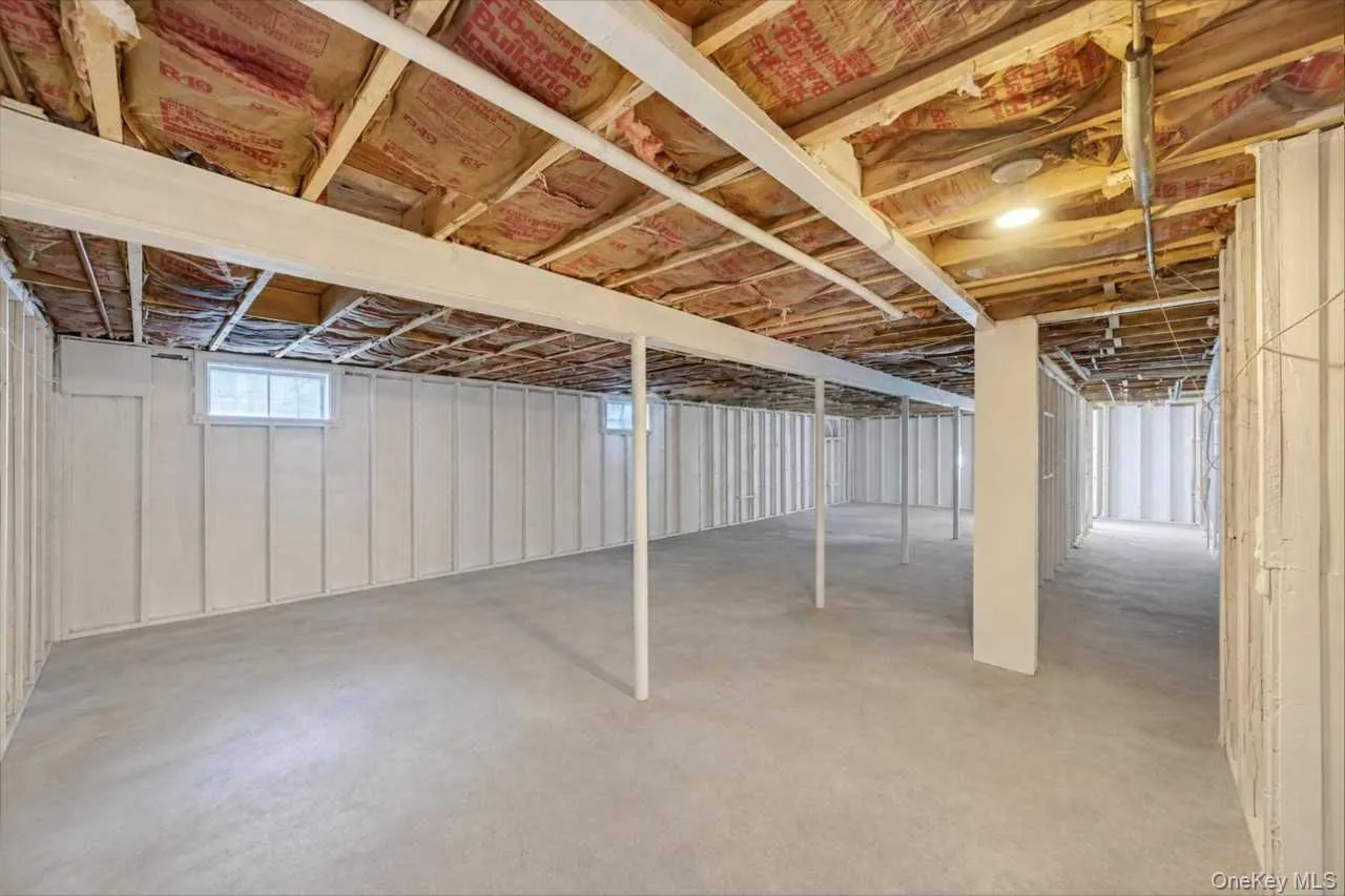 Expansive unfinished basement featuring concrete flooring and exposed ceiling joists Expansive unfinished basement featuring concrete flooring and exposed ceiling joists