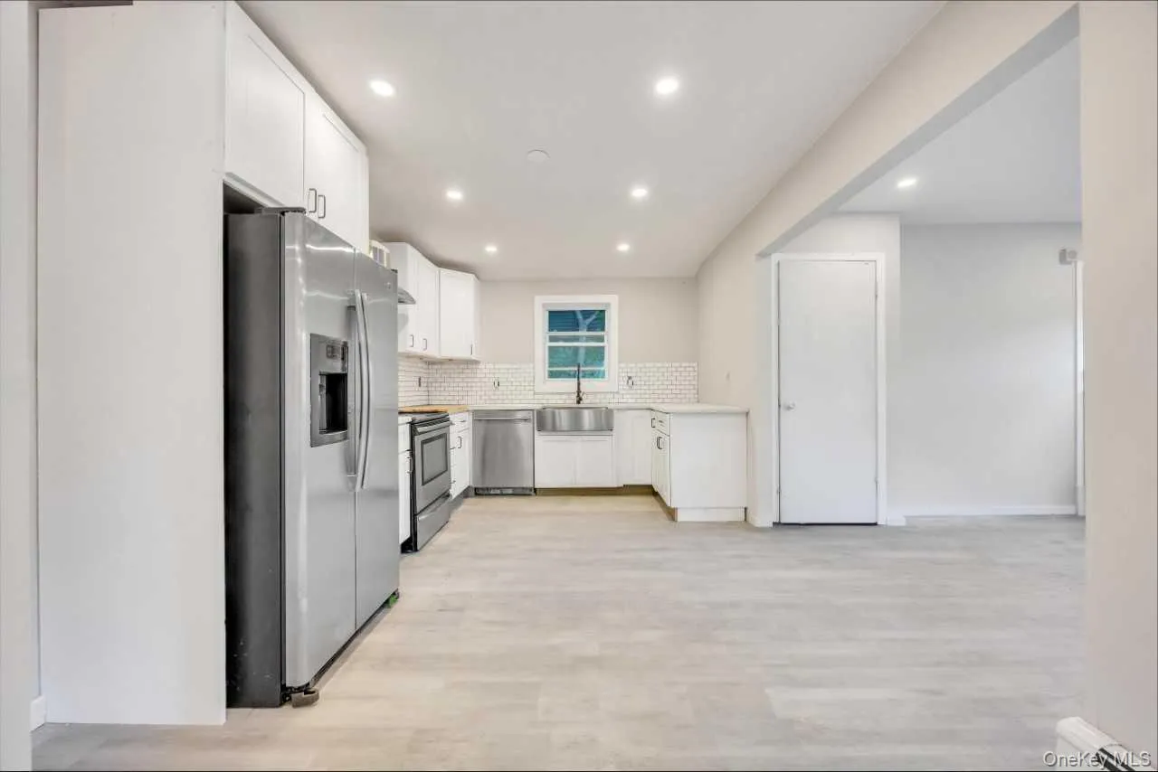 Bright kitchen featuring white cabinetry, stainless steel appliances, and light wood-finish flooring Bright kitchen featuring white cabinetry, stainless steel appliances, and light wood-finish flooring