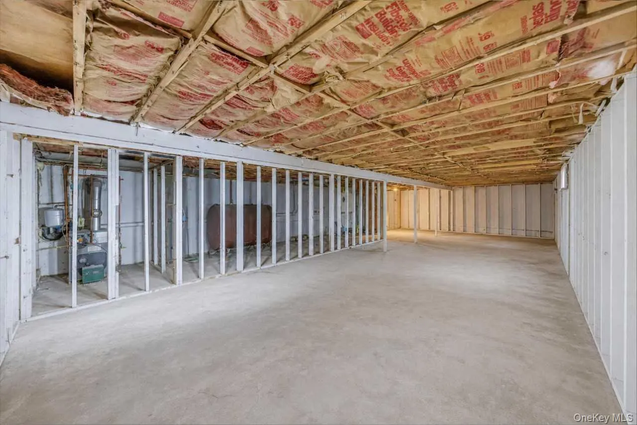 Expansive unfinished lower level with concrete flooring, exposed ceiling joists with insulation, and framed partition walls Expansive unfinished lower level with concrete flooring, exposed ceiling joists with insulation, and framed partition walls