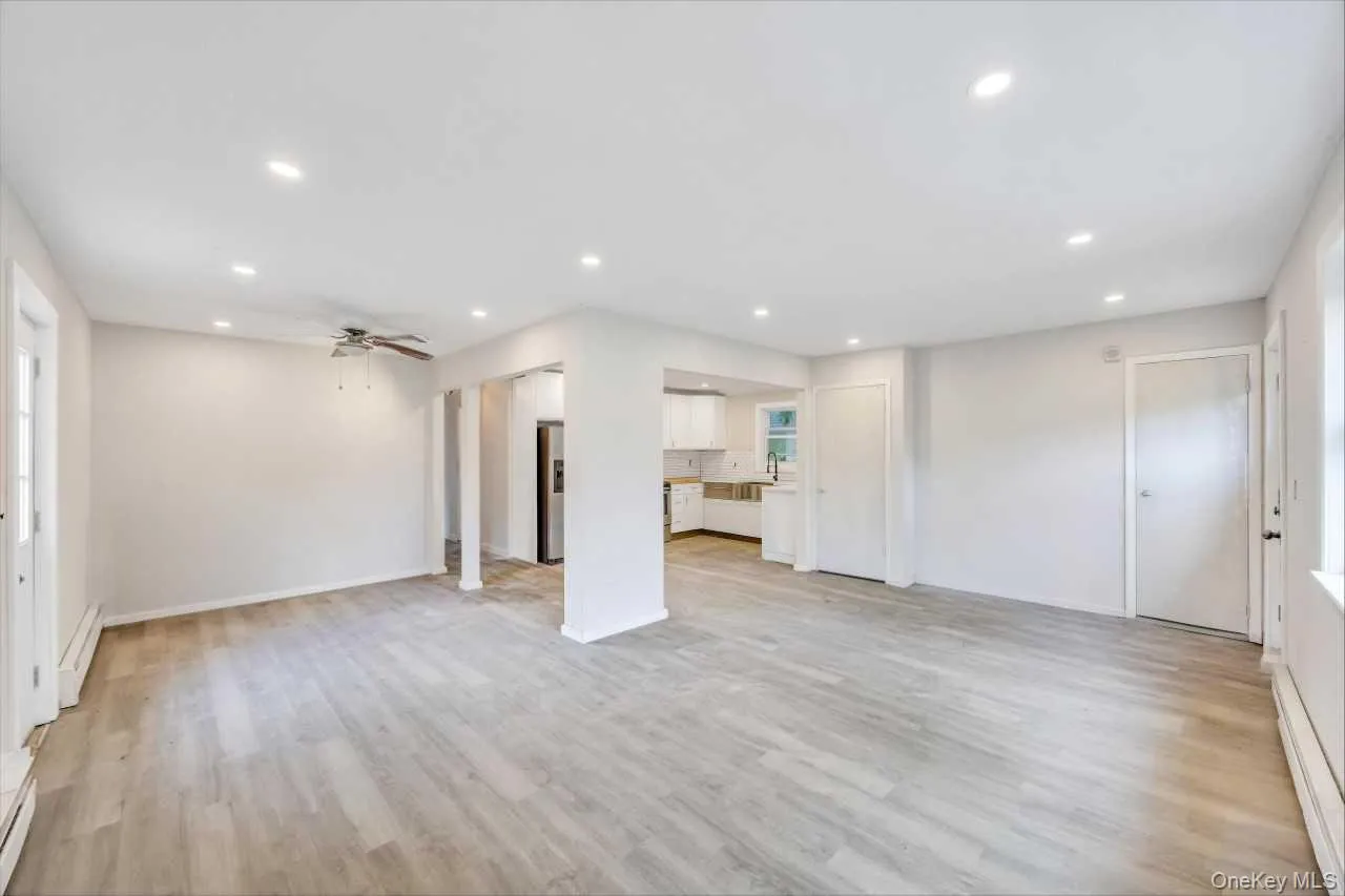 Spacious open-concept interior featuring light wood-finish flooring, recessed lighting, and a ceiling fan Spacious open-concept interior featuring light wood-finish flooring, recessed lighting, and a ceiling fan