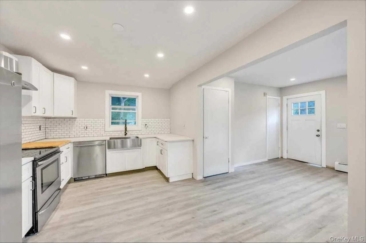 Kitchen featuring white shaker cabinetry, subway tile backsplash, stainless steel appliances, and a farmhouse sink Kitchen featuring white shaker cabinetry, subway tile backsplash, stainless steel appliances, and a farmhouse sink