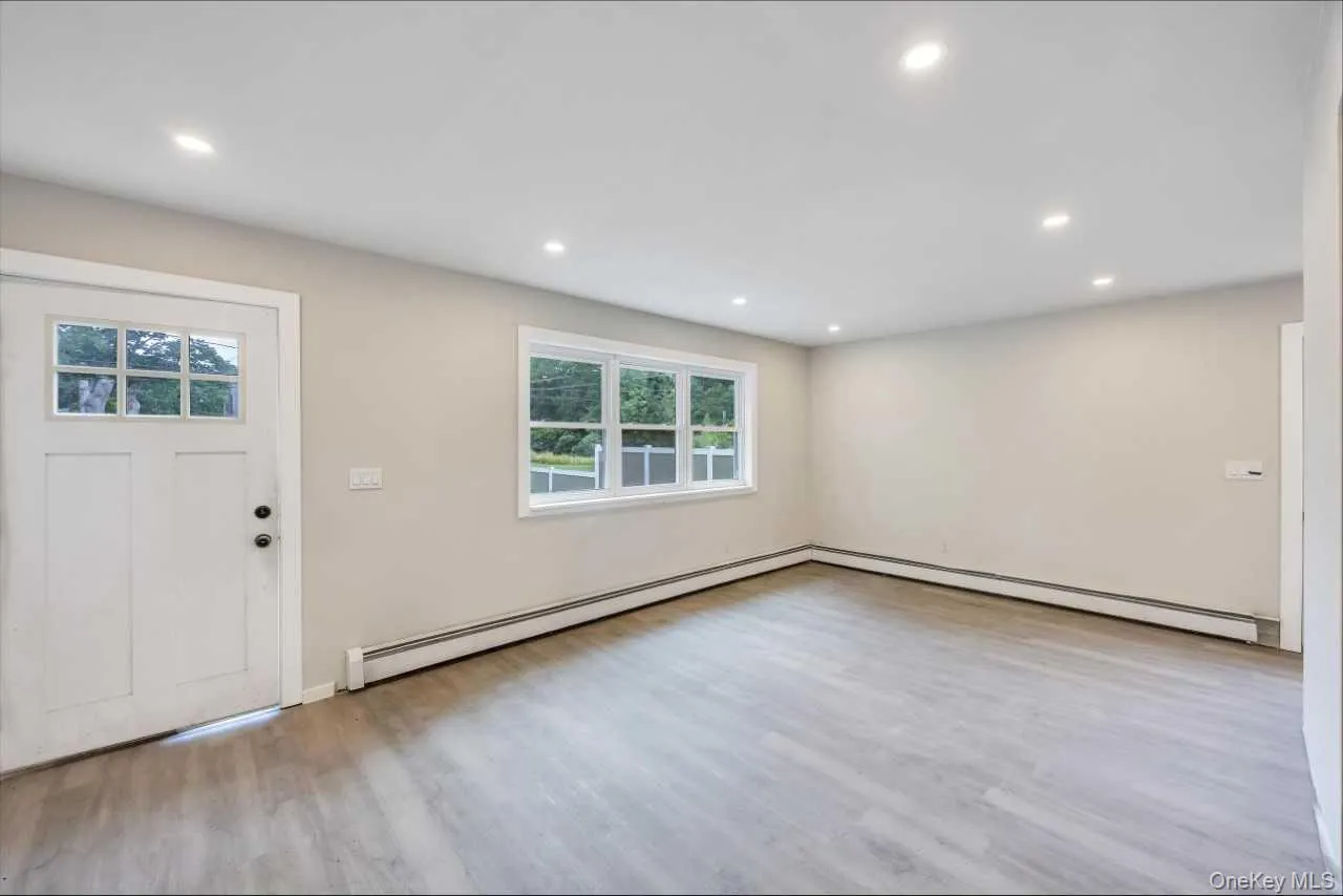 Spacious room featuring light wood-finish flooring, recessed lighting, and a multi-pane entry door Spacious room featuring light wood-finish flooring, recessed lighting, and a multi-pane entry door