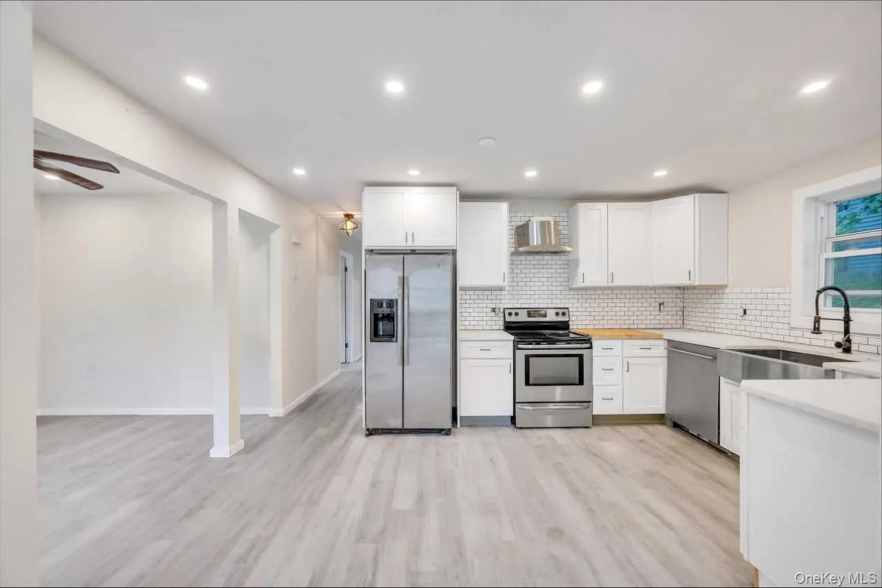 Modern kitchen featuring white shaker cabinetry, stainless steel appliances, white subway tile backsplash, and light wood-finish flooring Modern kitchen featuring white shaker cabinetry, stainless steel appliances, white subway tile backsplash, and light wood-finish flooring