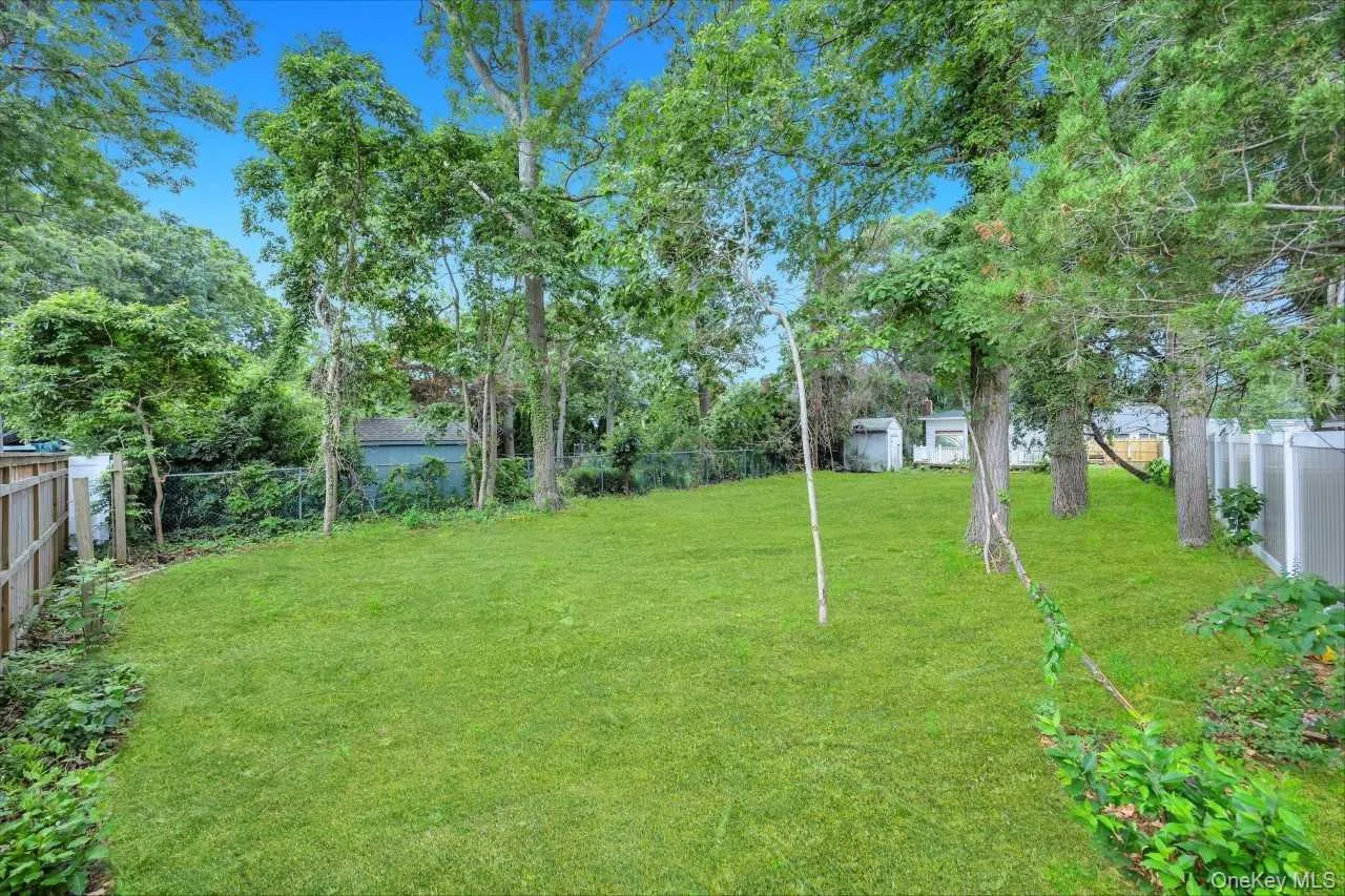 Expansive lawn area featuring mature trees and partial fencing Expansive lawn area featuring mature trees and partial fencing